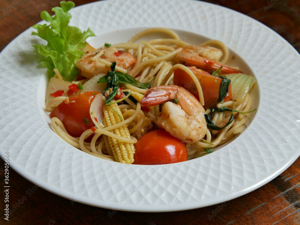 Spicy spaghetti with shrimps close-up on a plate on wooden table. horizontal top view from above.
Spicy spaghetti with shrimps close-up on a plate on wooden table. horizontal top view from above.
