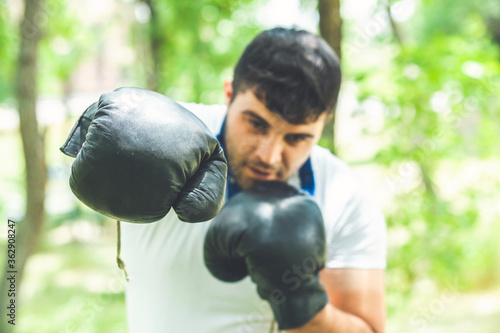 Boxing training endurance. Man athlete concentrated face with sport gloves practicing boxing nature background. Boxer ready to fight. Sportsman boxer training with boxing gloves.