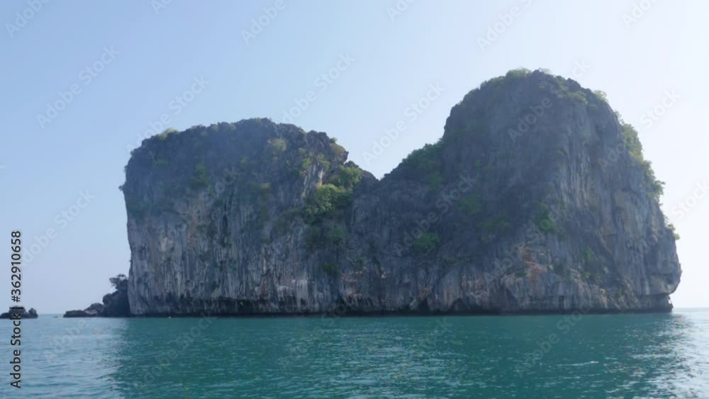 Ultra slow motion shot tilting up from water to giant limestone rock with vegetation in Thailand Ultra slow motion shot tilting up from water to giant limestone rock with vegetation in Thailand