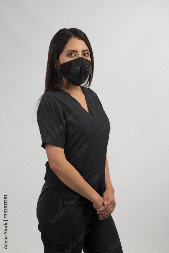 beauty nurse dressed in black with mask, standing in studio with gray background beauty nurse dressed in black with mask, standing in studio with gray background