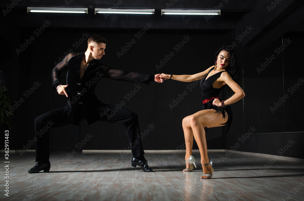 Ballroom dancers. The guy with the girl is engaged in ballroom dancing. Ballroom dancing. Dancing. The guy with the girl dancing in a dark room.
