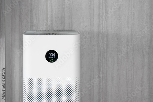 Indoor air purifier with digital monitor screen in living room, show air quality in the room and air pollution levels in the room. with wood laminate wall background