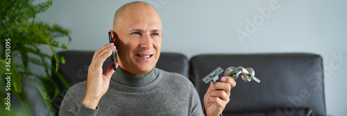 Man man holds furniture fittings and talking on mobile phone at sofa.