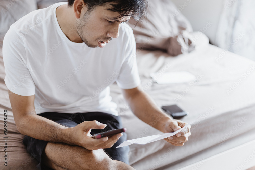 Asian people use a smartphone and calculate and pay after receiving an invoice in the bedroom. Online bill payment concepts Asian people use a smartphone and calculate and pay after receiving an invoice in the bedroom. Online bill payment concepts