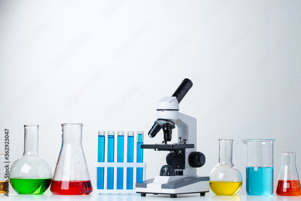 Lab microscope with laboratory glassware on desk Lab microscope with laboratory glassware on desk