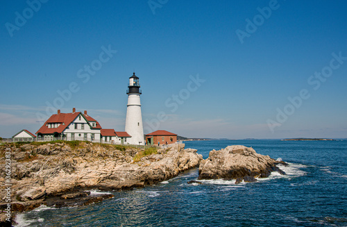 A view of Portland lighthouse standing on the rocks on a bright sunny day.
