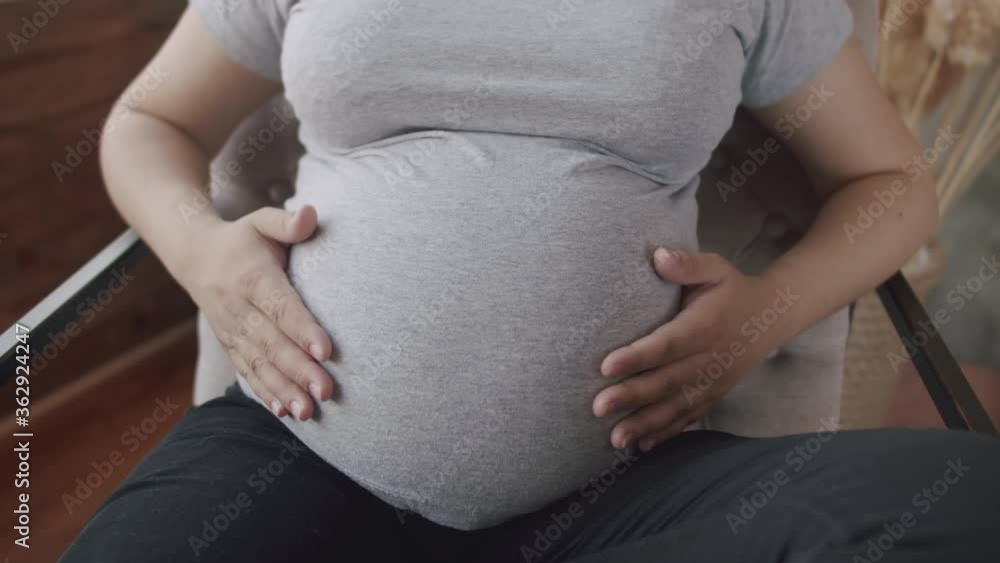 Movement of the camera around the pregnant belly, which is stroked by