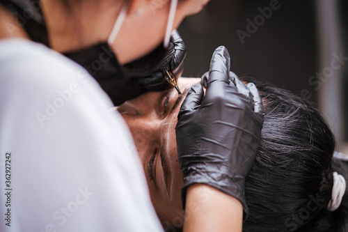 Girl artist paints an eyebrow tattoo. The process of tattooing. Permanent makeup