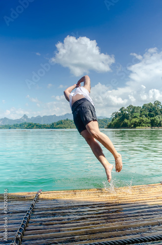 Tourist  jumping into the lake from the raft. Adventure trips on summer holidays. Outdoor activity relaxing concept.