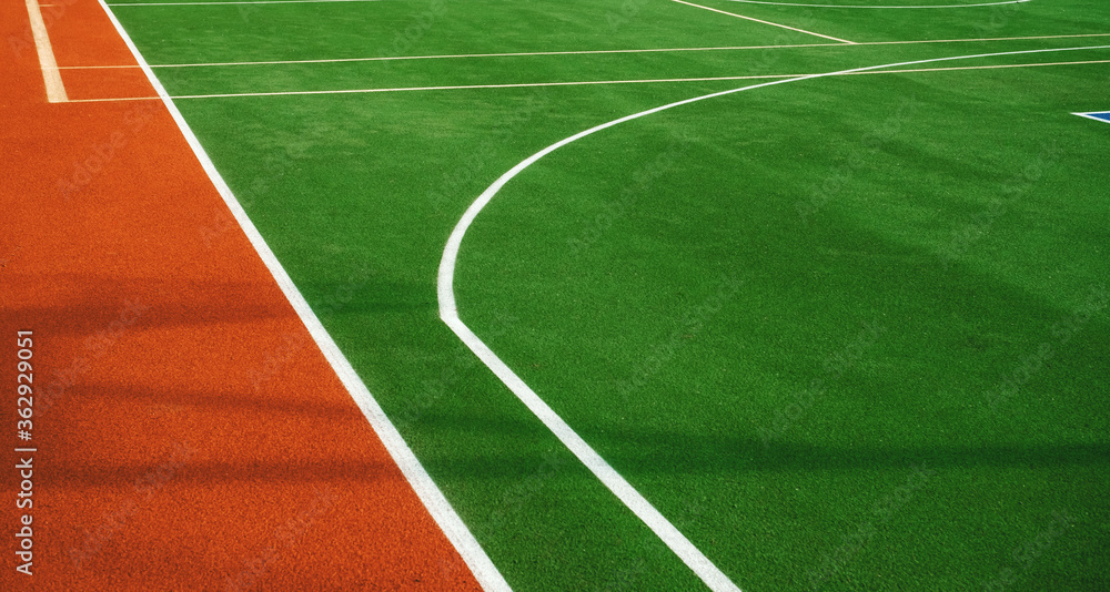 Artificial grass with markings on the sports ground for playing tennis and basketball, close-up.