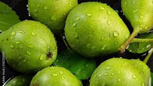 Green pears and drops with leaves are in the water on a dark background