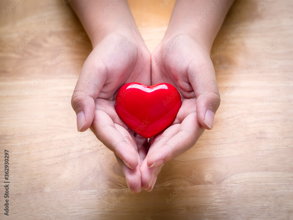 Hands of child holding a red heart on a wooden table for love and concern of all family members. Adoption foster family, romance, healthy and valentine day concept. Hands of child holding a red heart on a wooden table for love and concern of all family members. Adoption foster family, romance, healthy and valentine day concept.