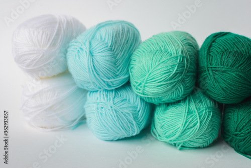 acrylic soft pastel green, azure and white colored wool yarn thread skeins row on white background, side view, horizontal stock photo image background with copy space for text
