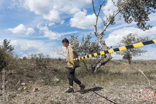 A man walks in a protective coat through a signal tape. Stalker in the world of post-apocalypse. photo