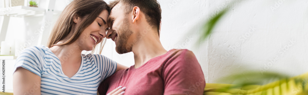 Fototapeta premium smiling beautiful young couple hugging at home, panoramic orientation