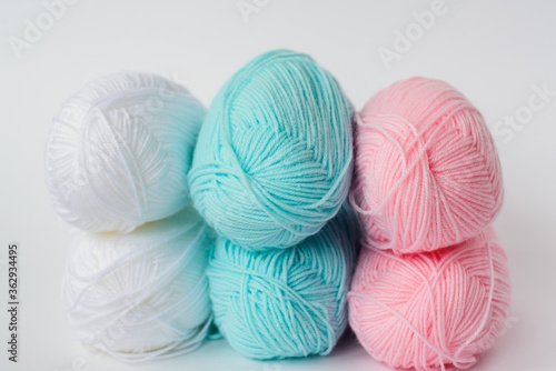 acrylic soft pastel pink, azure and white colored wool yarn thread skeins row on white background, side view, horizontal stock photo image background