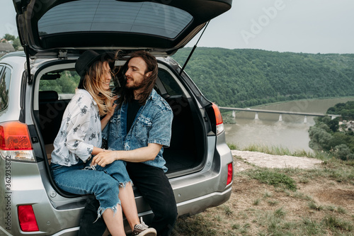 Young Stylish Traveling Hipsters Having Fun Sitting in Car Trunk Near the River Canyon, Travel and Road Trip Concept © Romvy