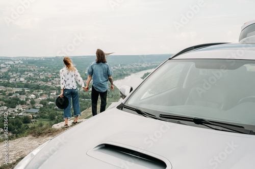 Young Trendy Traveling Couple Having Fun Near the Car on Top of Hill, Travel and Road Trip Concept