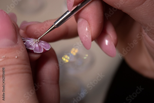 the process of doing manicure. Closeup of hands of professional manicurist, applying little stones on nails. Concept of doing manicure. beauty concept. Gel polish, shellac photo