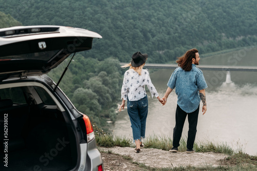 Young Trendy Traveling Couple Having Fun Near the Car on Top of Hill, Travel and Road Trip Concept © Romvy