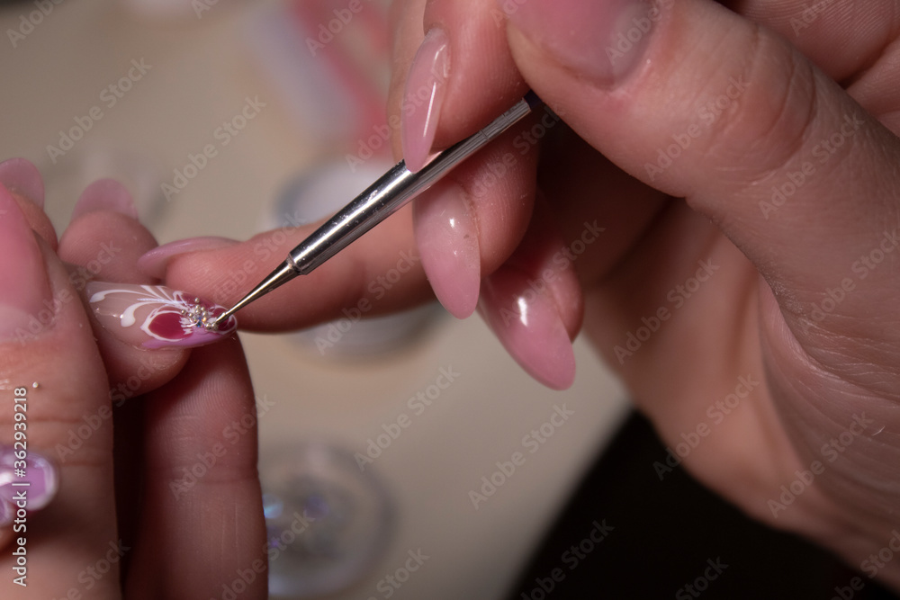 the process of doing manicure. Closeup of hands of professional manicurist, applying little stones on nails. Concept of doing manicure. beauty concept. Gel polish, shellac the process of doing manicure. Closeup of hands of professional manicurist, applying little stones on nails. Concept of doing manicure. beauty concept. Gel polish, shellac