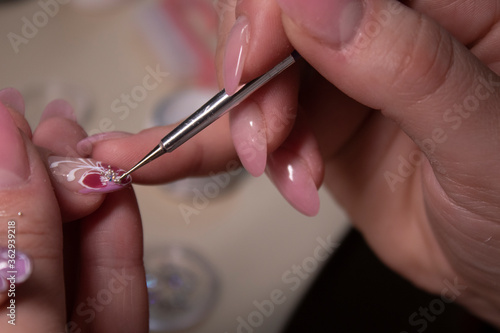 the process of doing manicure. Closeup of hands of professional manicurist  applying little stones on nails. Concept of doing manicure. beauty concept. Gel polish  shellac