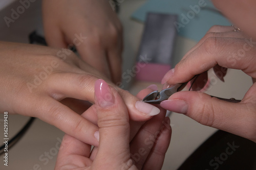 the process of doing manicure. Closeup of hands of professional manicurist  removing cuticle in salon. Concept of doing manicure and fingernails cleaning. beauty concept. Gel polish  shellac