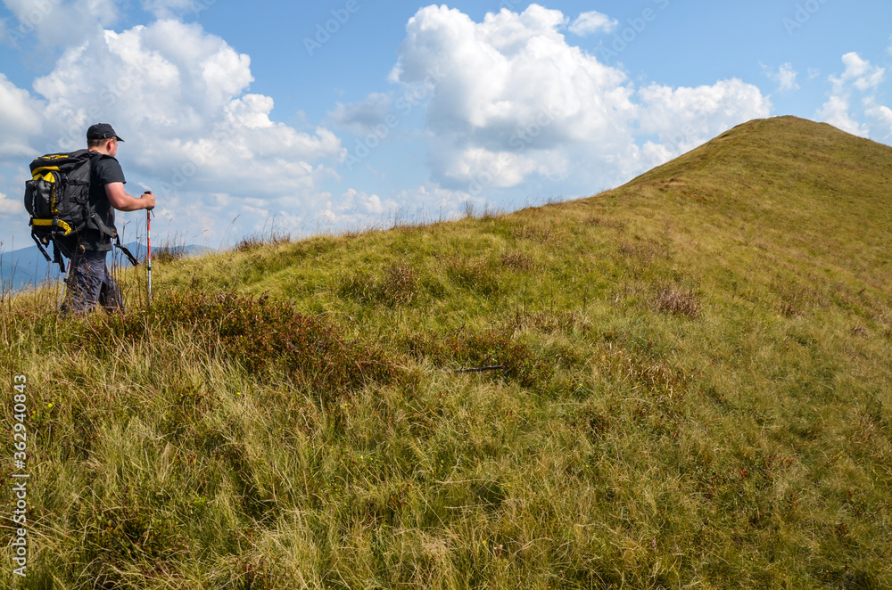 Man tourist with a backpack overcomes the last steps on the way to the mountain peak. Carpathians, Ukraine. Concept of travel and active lifestyle Man tourist with a backpack overcomes the last steps on the way to the mountain peak. Carpathians, Ukraine. Concept of travel and active lifestyle