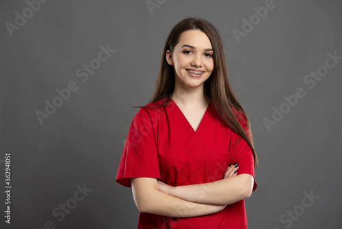 Portrait of a confident young nurse with braces wearing red scrubs
