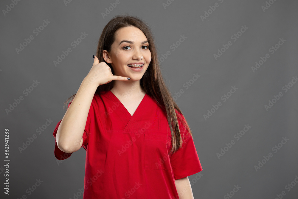 Smiling long hair brunette nurse makes call me gesture Smiling long hair brunette nurse makes call me gesture