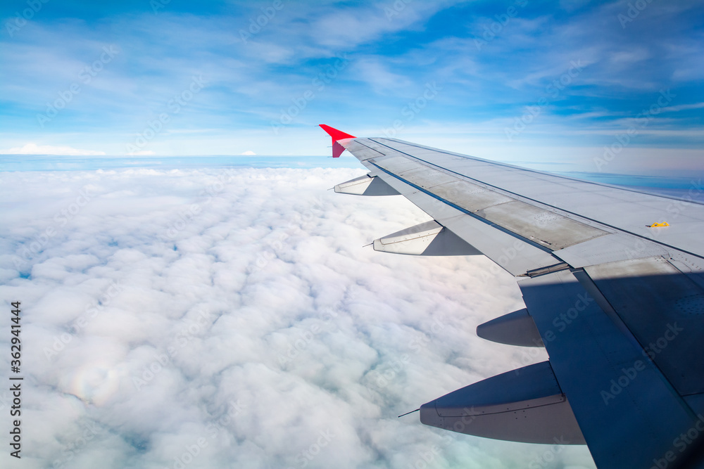 Obraz premium Wing of an airplane flying above the morning clouds, copy space for text.