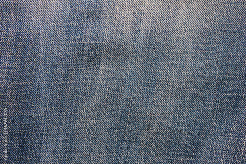 Denim jeans material surface background. Seamless smooth light blue denim clothing, blank jean fiber close up top view 