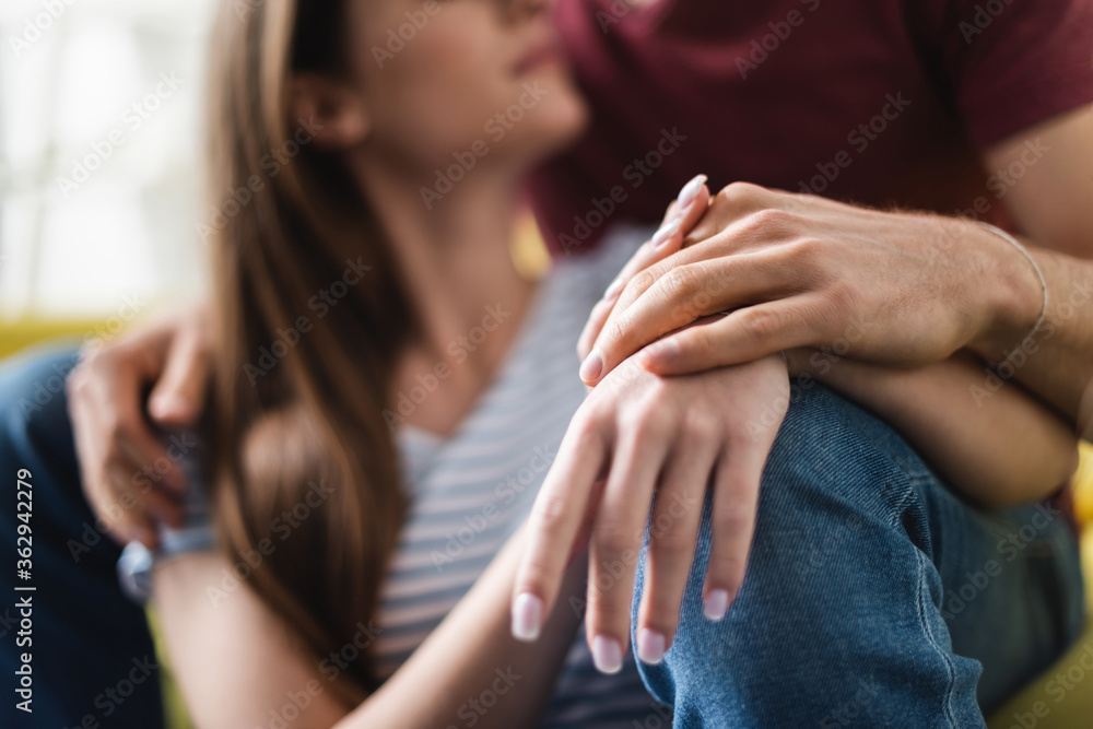 Fototapeta premium cropped view of couple hugging and holding hands at home, selective focus