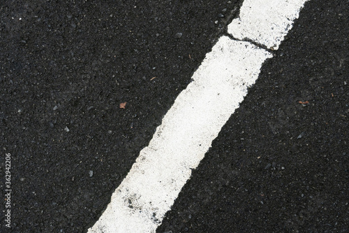 Color of white traffic lines with cracks on wet asphalt road. © thongchainak