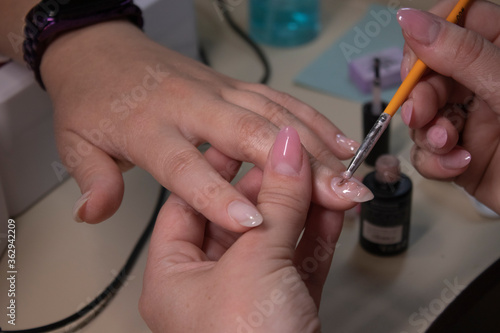the process of doing manicure. Closeup of hands of professional manicurist  applying nail polish. Concept of doing manicure and fingernails cleaning. beauty concept. Gel polish  shellac