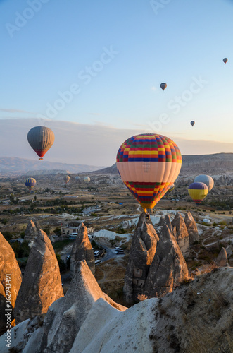 Color hot air balloons flying at sunrise over stone formations in valley of Cappadocia,Turkey