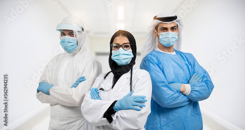 Successful team of Arabic medical doctors are looking at camera while standing in hospital with arms crossed male and female doctors in protective gear fighting coronavirus COVID-19.