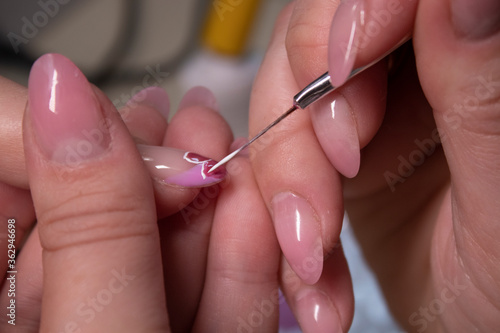 the process of doing manicure. Closeup of hands of professional manicurist  painting little flowers on nails. Concept of doing manicure. beauty concept. Gel polish  shellac