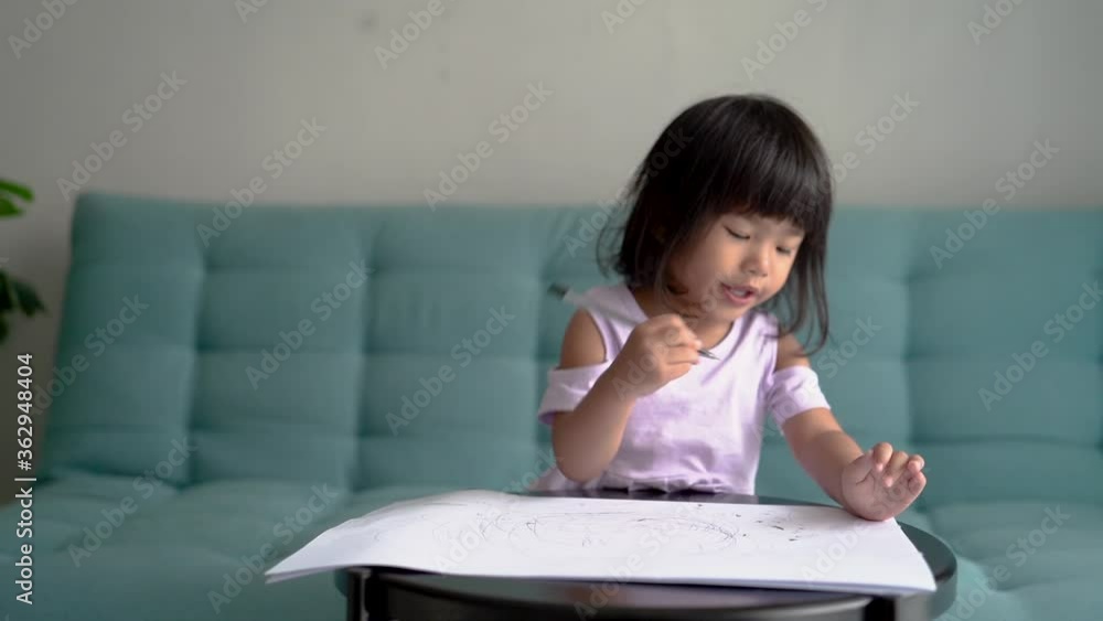 little girl is drawing using a pen in the living room