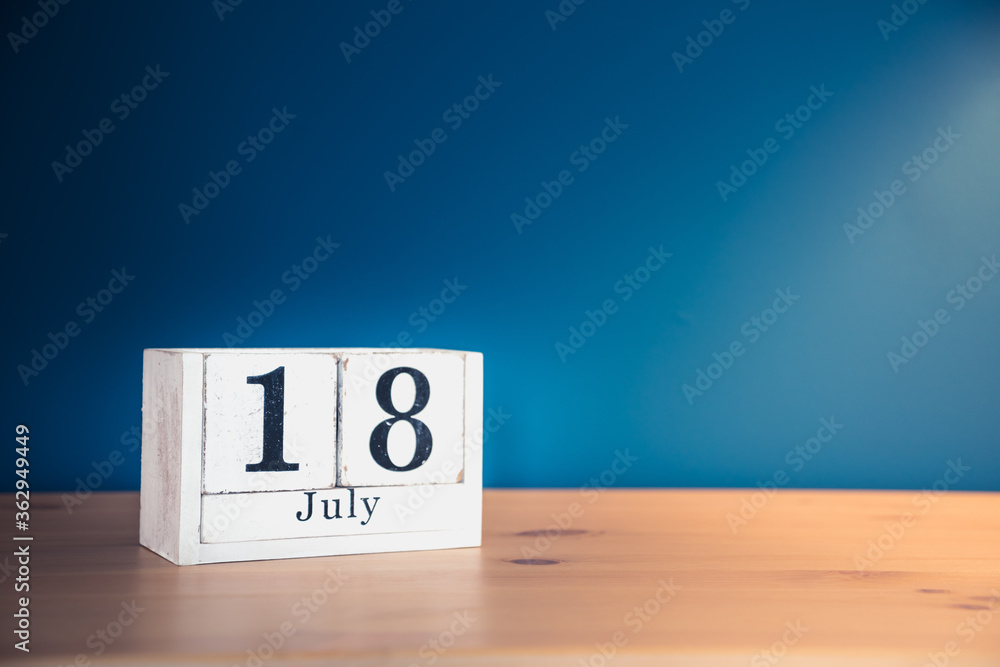 July 18 - white calendar blocks on wooden table against vintage blue background July 18 - white calendar blocks on wooden table against vintage blue background