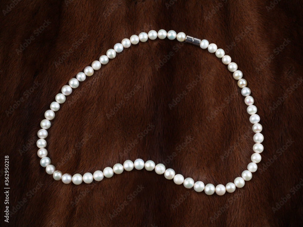Pearl necklace on brown fur background