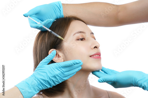 Hands of beautician injecting Botulinum toxin type A to asian woman in eye area.