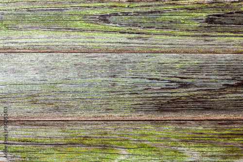 Horizontal wooden background from three gray planks with cracks and traces of old green paint