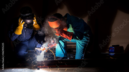 Workers in safety clothing welding steel parts in industrial plants.
