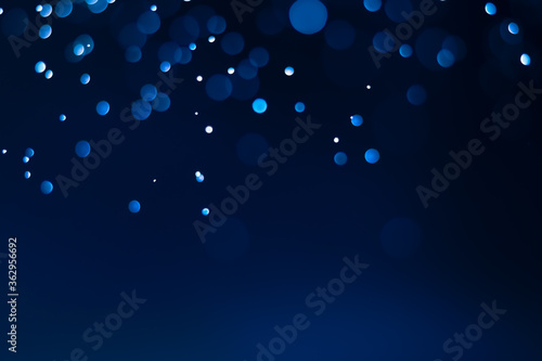 Abstract bokeh, defocused of water drops reflects light on dark blue background.