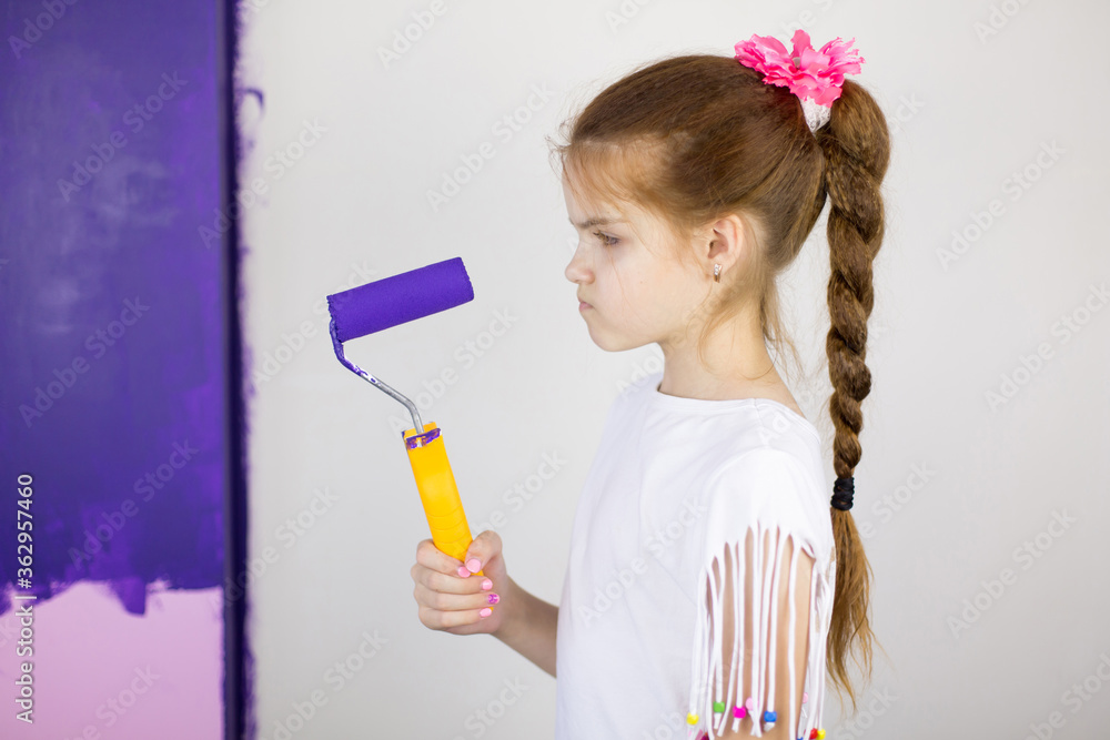 Little girl painting wall in room