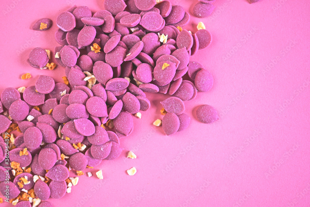 Fototapeta premium Pink chocolate drops scattered on pink background. Tablet for confectionary. Ruby chocolate made from ruby cocoa bean.