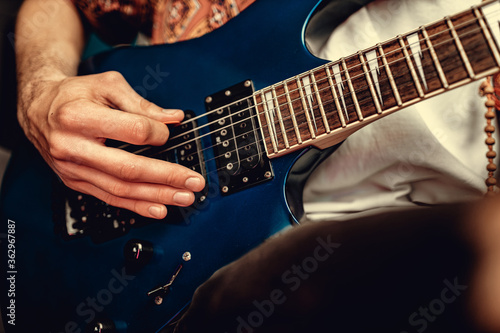 Close up of male hand playing electric guitar in the dark