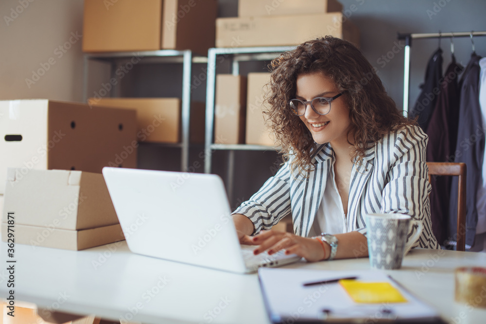 Young smiling entrepreneur working on laptop at her workplace. Confident online business owner working on laptop. Young smiling entrepreneur working on laptop at her workplace. Confident online business owner working on laptop.