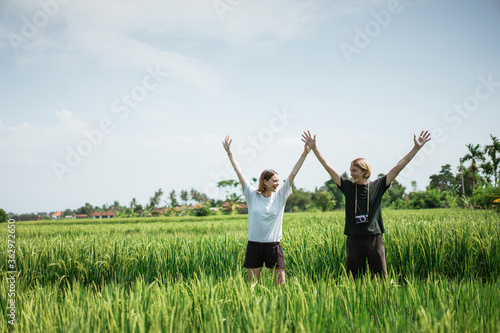 Couple pose in the middle of the rice field with exotic view in the bright sunny day